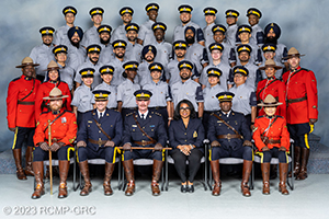 32 diverse pre-cadets assemble in uniform with program leaders in red serge for a graduation photo.