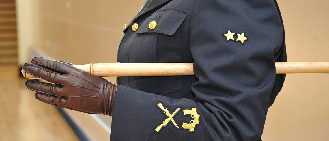 Close up of a Sergeant Major holding a pacing staff under her arm.