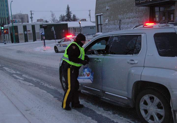 Les membres de la GRC remettent des feuillets d'information et des cannes de Noël à des automobilistes à Yellowknife. 