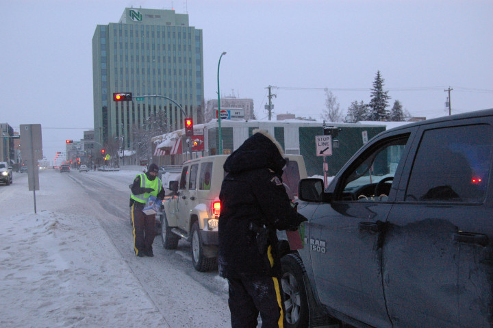 Les membres de la GRC remettent des feuillets d'information et des cannes de Noël à des automobilistes à Yellowknife. 