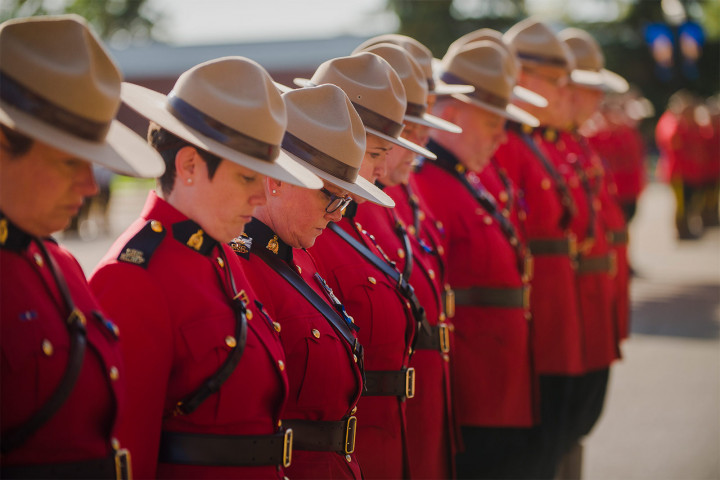 RCMP members in red serge bow their heads during a moment of silence.