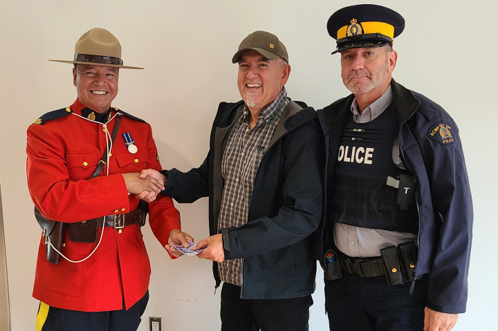 Cst. Jeff Chartrand (left) and Cst. Serge Montreuil (right) shake hands with Band member Fred Bellefeuille at Nipissing First Nation