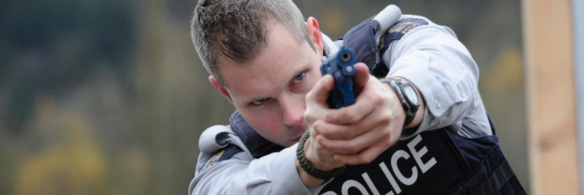 Police officer points training pistol.