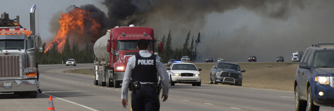 RCMP officer walks on road near forest fire.
