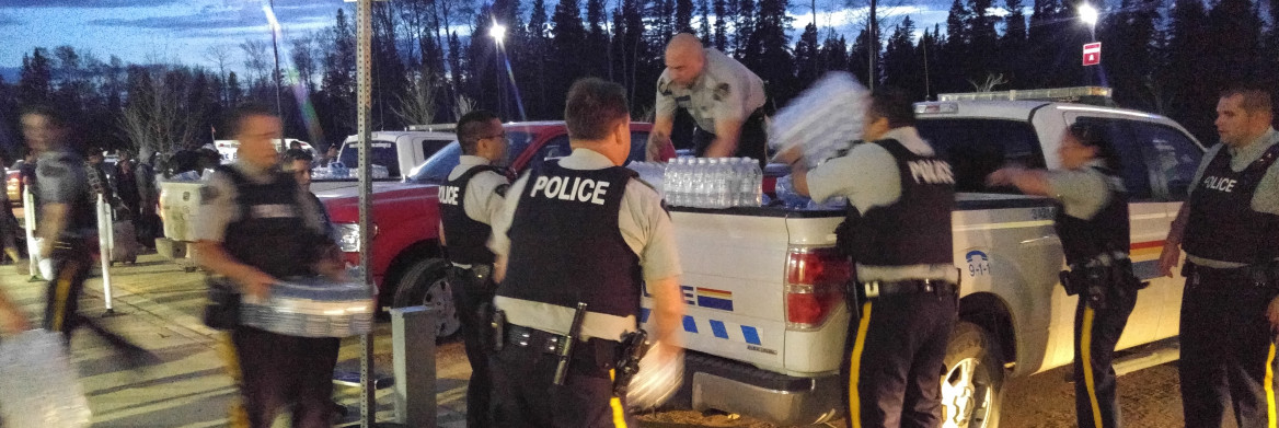 RCMP officers lift packs of water bottles off of a truck.
