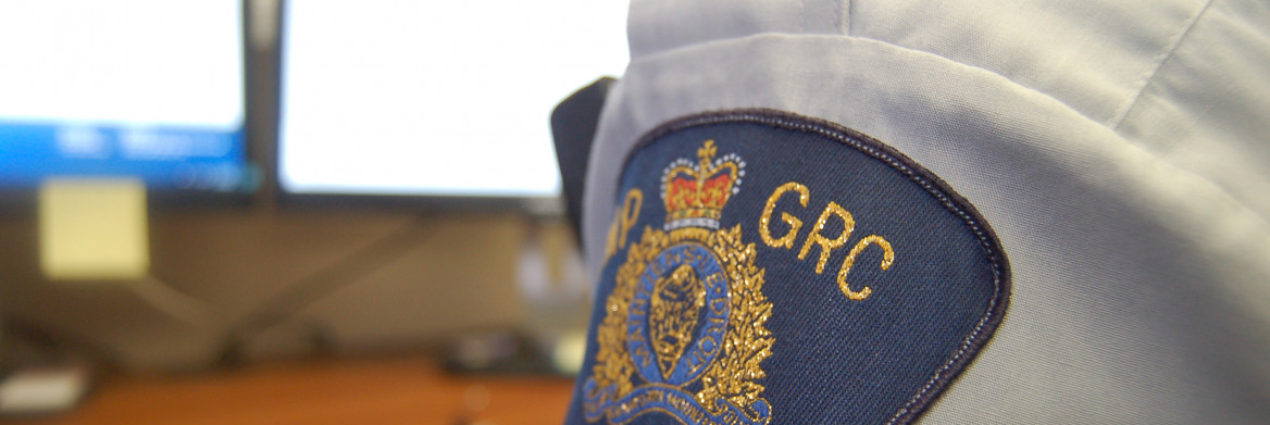 A uniformed RCMP officer sits at a computer. 