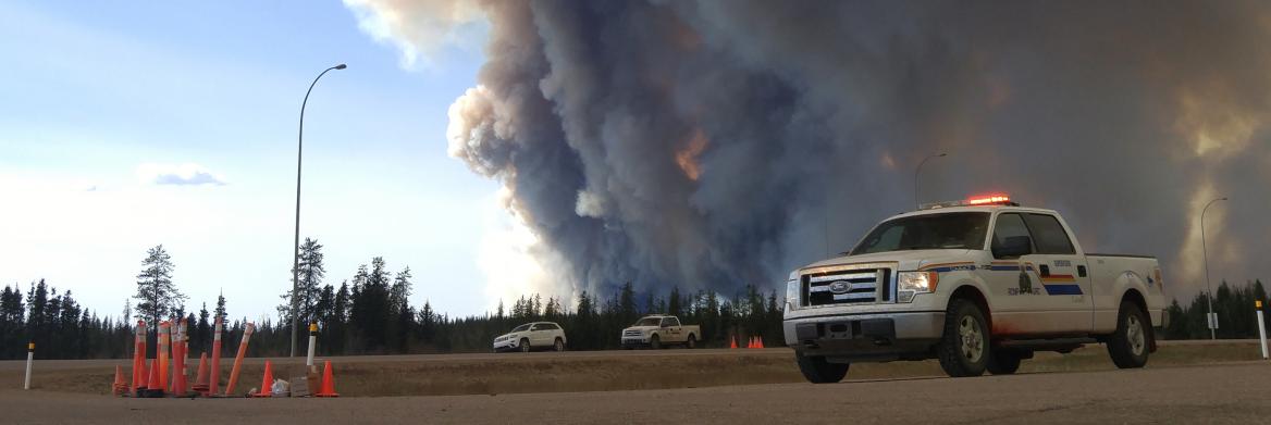 RCMP vehicle parked next to forest fire.
