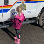School child colourfully drawing on a police vehicle using dry erase markers as part of the Colouring a Police Vehicle event.
