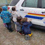 School children colourfully drawing on a police vehicle using dry erase markers as part of the Colouring a Police Vehicle event.