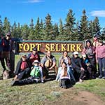 Group photo of Youth Canoe Trip participants taken in front of the Fort Selkirk sign