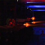 Cadets shoot their pistols in a dark range while red and blue lights flash above them.
