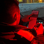 A cadet writes in his notebook while sitting in his vehicle at night.