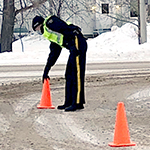A cadet places traffic cones at the scene of a staged vehicle collision