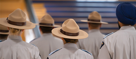 Cadets stand together looking forward. Some cadets are wearing Stetson hats and one wears a navy turban.
