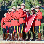 A group of cadets in red serge work together to fold the Canada flag. 
