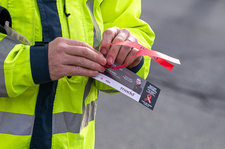 Deux mains vues de près tiennent un ruban rouge et un dépliant de MADD Canada.