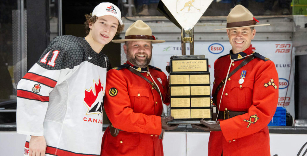 (De gauche à droite) Matthew Schaefer, défenseur d'Équipe Canada Blanc, l'agent Lorenz Sanders et le sergent d'état-major Michael Robinson avec le trophée du hockey mondial U-17