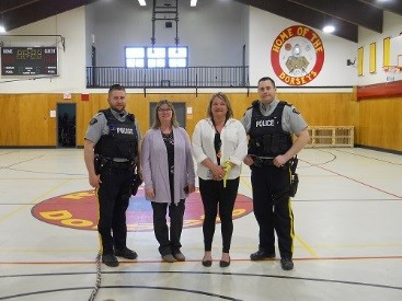 Two RCMP officers stood with two female volunteers in gym of youth centre.