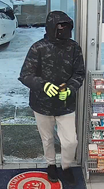 Suspect wearing a balaclava face mask, black and grey camo jacket, grey sweat pants with a black strip and yellow gloves