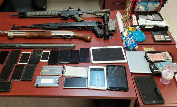 Trois armes à feu, armes et appareils électroniques, argent en espèces et autres articles saisis sur un bureau