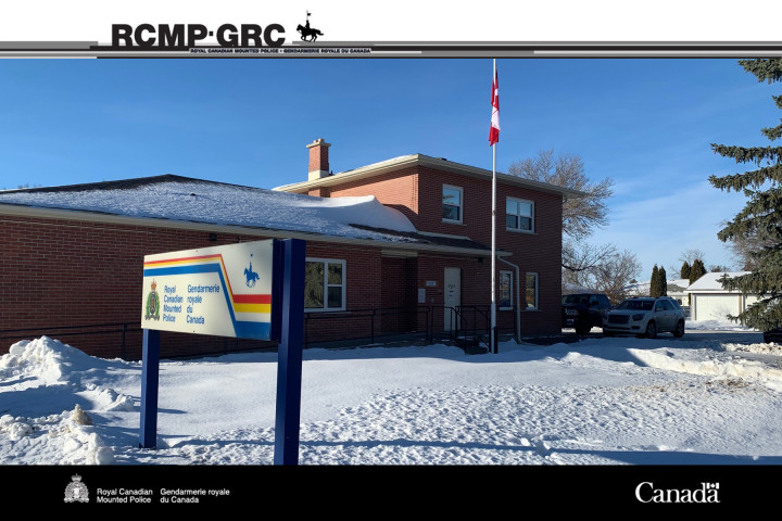Kindersley RCMP Detachment building with snow outside and two vehicles parked in driveway
