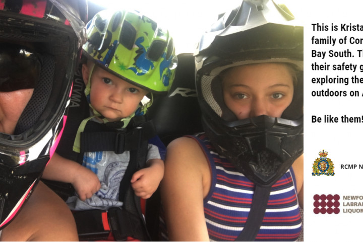 A family is seated in a side by side wearing seat belts and helmets.