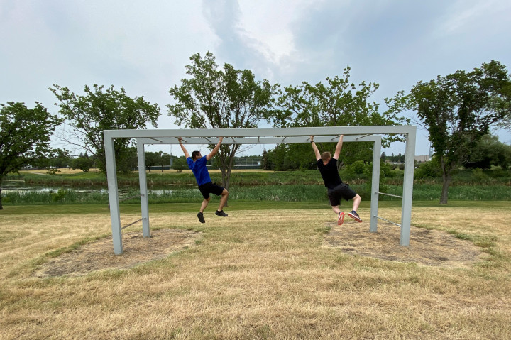 Two cadets swing on monkey bars during an obstacle course.