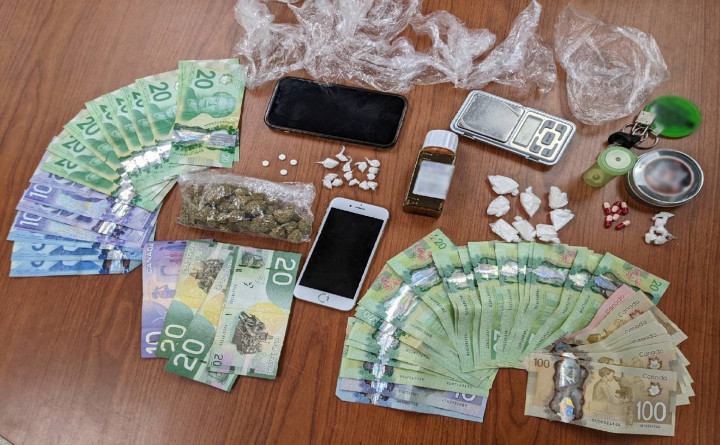 Money, drugs and prescription medications seized during exeution of a search warrant laid out on a table
