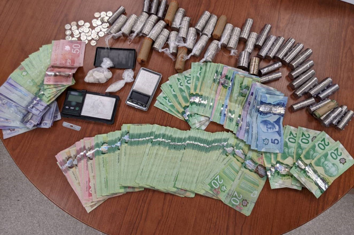 Money, drugs and prescription medications seized during exeution of a search warrant laid out on a table