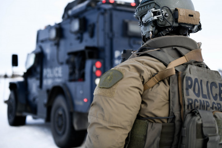 A uniformed officer stands near a tactical vehicle 