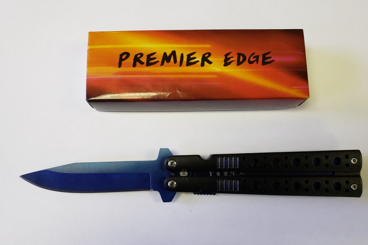 Un étui orange et brun portant la marque Premier Edge avec un couteau noir à ouverture automatique, en position ouverte. Il s'agit d'une arme prohibée.