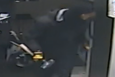 Image floue d'un suspect avec des vêtements noirs portant une massue à l'intérieur du PharmaChoice à Bonne Bay lors d'un vol avec effraction.