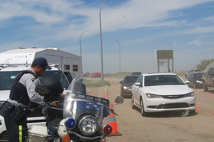 Véhicules policiers et véhicules civils stoppés lors d'un contrôle routier près de Chamberlain. Des policiers discutent avec les conducteurs des véhicules.