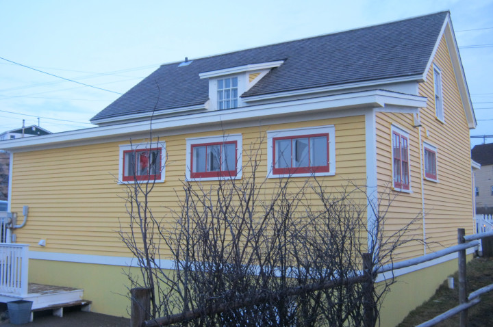 Three broken windows are shown on a yellow, red and white home. 