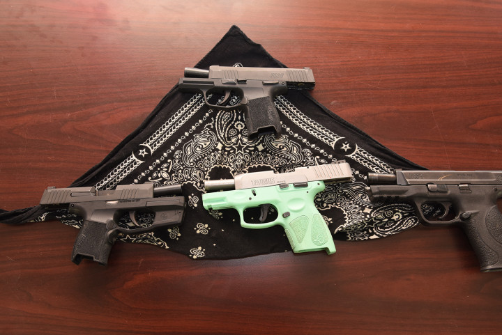 Handguns and a black bandanna on a table.