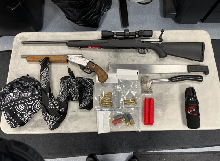 A variety of weapons and ammunition seized by police in Meadow Lake; items laid out on table.