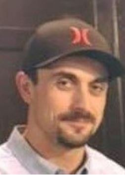 A white man with a goatee wearing a collared shirt and ball cap. 