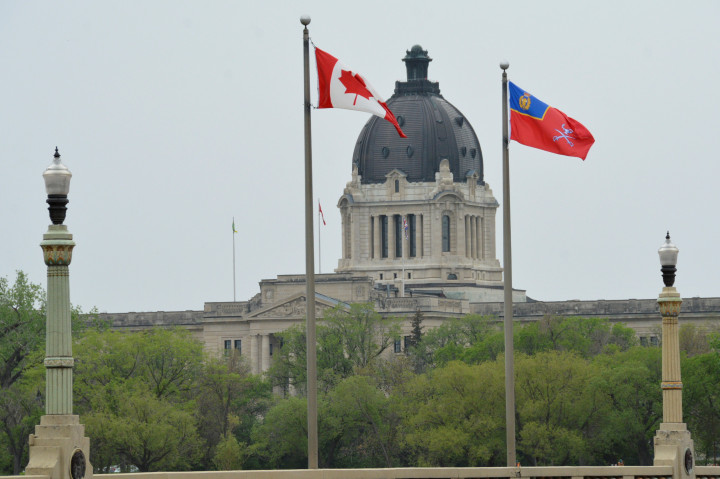 RCMP and Canadian flags are seen flying on the Albert Street Memorial Bridge with the Saskatchewan Legislative Building in the background.