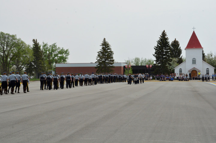 Des cadets et des employés marchent dans un défilé spécial du sergent-major. Des employés les regardent au loin.