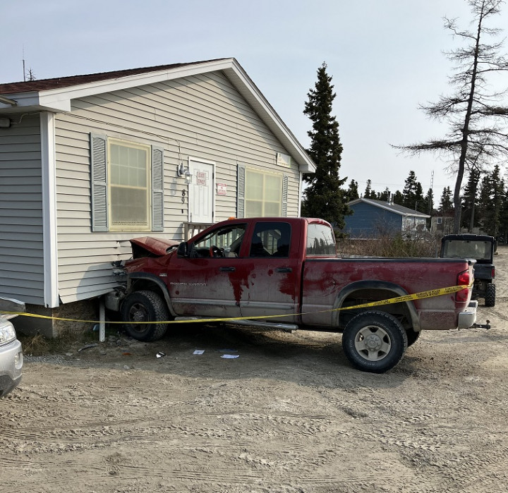 A burgundy Dodge Ram truck rests against a building. The vehicle has front-end damage.