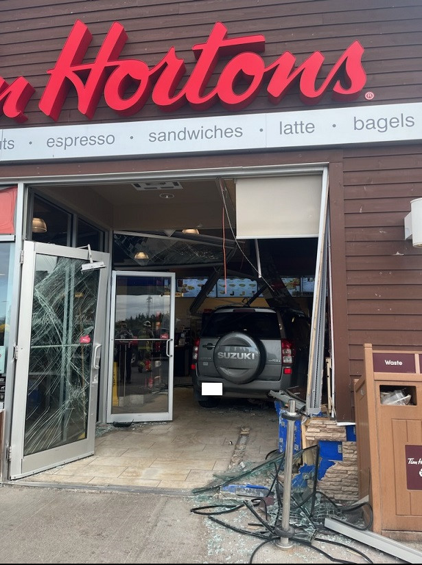 : L'entrée du Tim Hortons a subi des dommages importants. Dans la photo on aperçoit le VUS à l'intérieur du commerce.