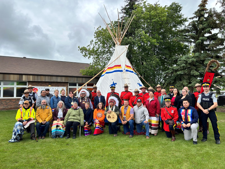 Meadow Lake RCMP officers and members of the community posing for a photo in front of a Tipi