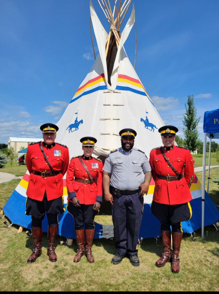 Members in Red Serge standing in front of a Tipi