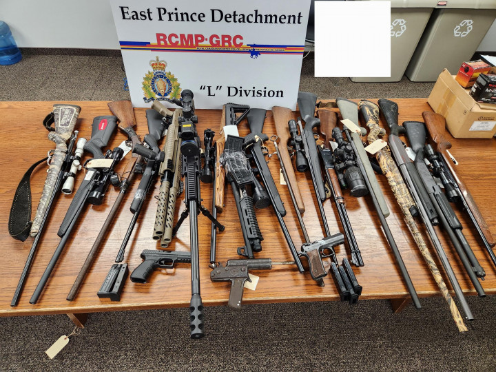 19 armes, dont des armes d'épaule et des armes de poing à autorisation restreinte, sont exposées sur une table avec un panneau indiquant East Prince Detachment G-R-C L- Division