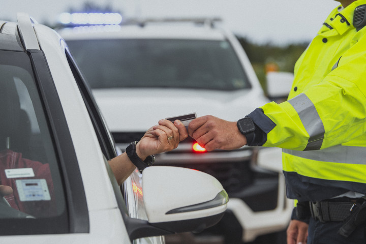 driver handing over license to police officer through car window