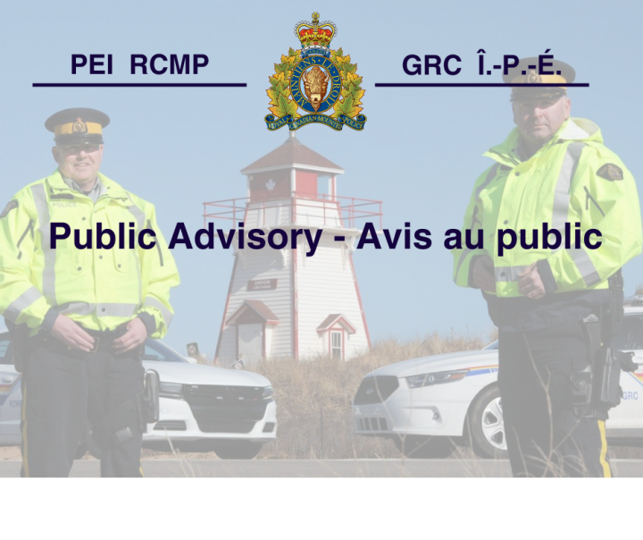 Two RCMP officers in high visibility yellow in front of a lighthouse