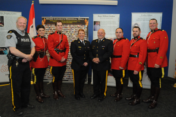 Eight uniformed police officers are standing smiling. Photo credit: Joe Gibbons, The Telegram
