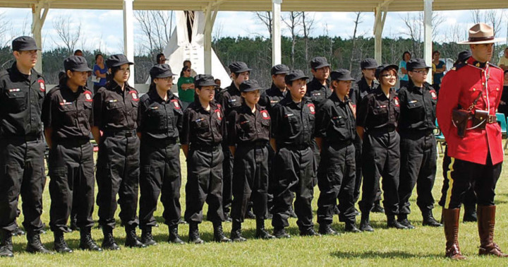 Cadets dressed in uniform behind a RCMP police officer in red serge. 