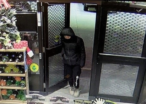 Une femme portant un capuchon tient la porte du commerce.
