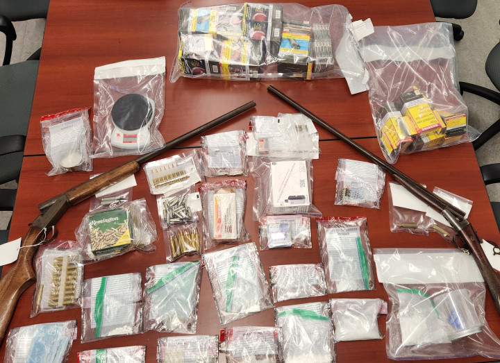 Seized items, including cocaine and methamphetamine in baggies and two firearms, arranged on a table